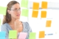 Concentrated female artist looking at colorful sticky notes at the office