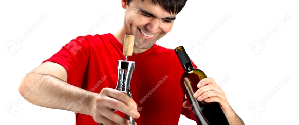 A smiling man with cork screw, looking inside uncorked bottle of wine