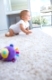 Side view of a cute baby crawling on carpet at home