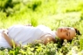 Beautiful pregnant woman relaxing on grass in the spring park