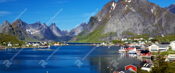 Scenic town of Reine, Norway on sunny summer day with picturesque fjord and surrounding mountain peaks