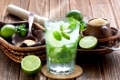 Mojito cocktail delicious summer drink with lime, mint and ice on rustic wooden background 
